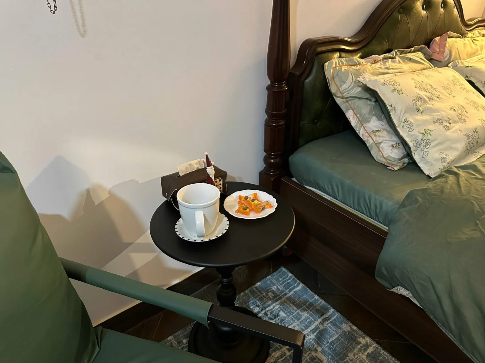 A small round table with tea and sweets beside the bed
