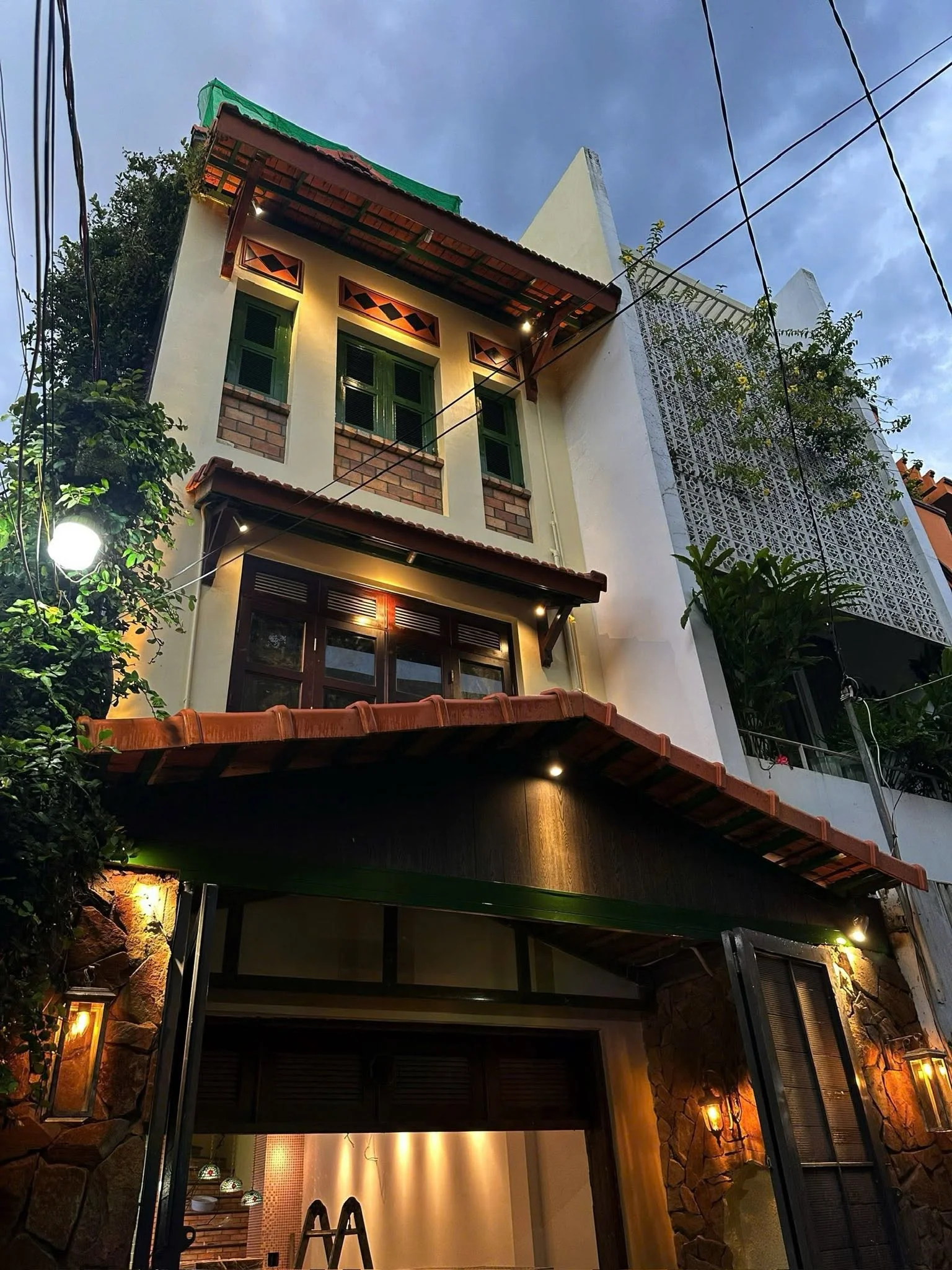 The ChiMi Homestay facade at dusk, red tiled roof and warm lamps